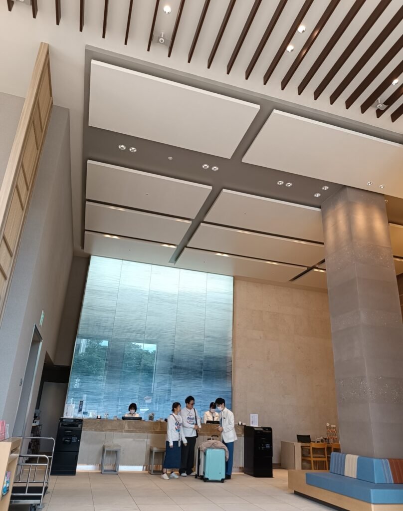 Hotel guests checking in with luggage at a modern hotel front desk, with lobby seating in the background